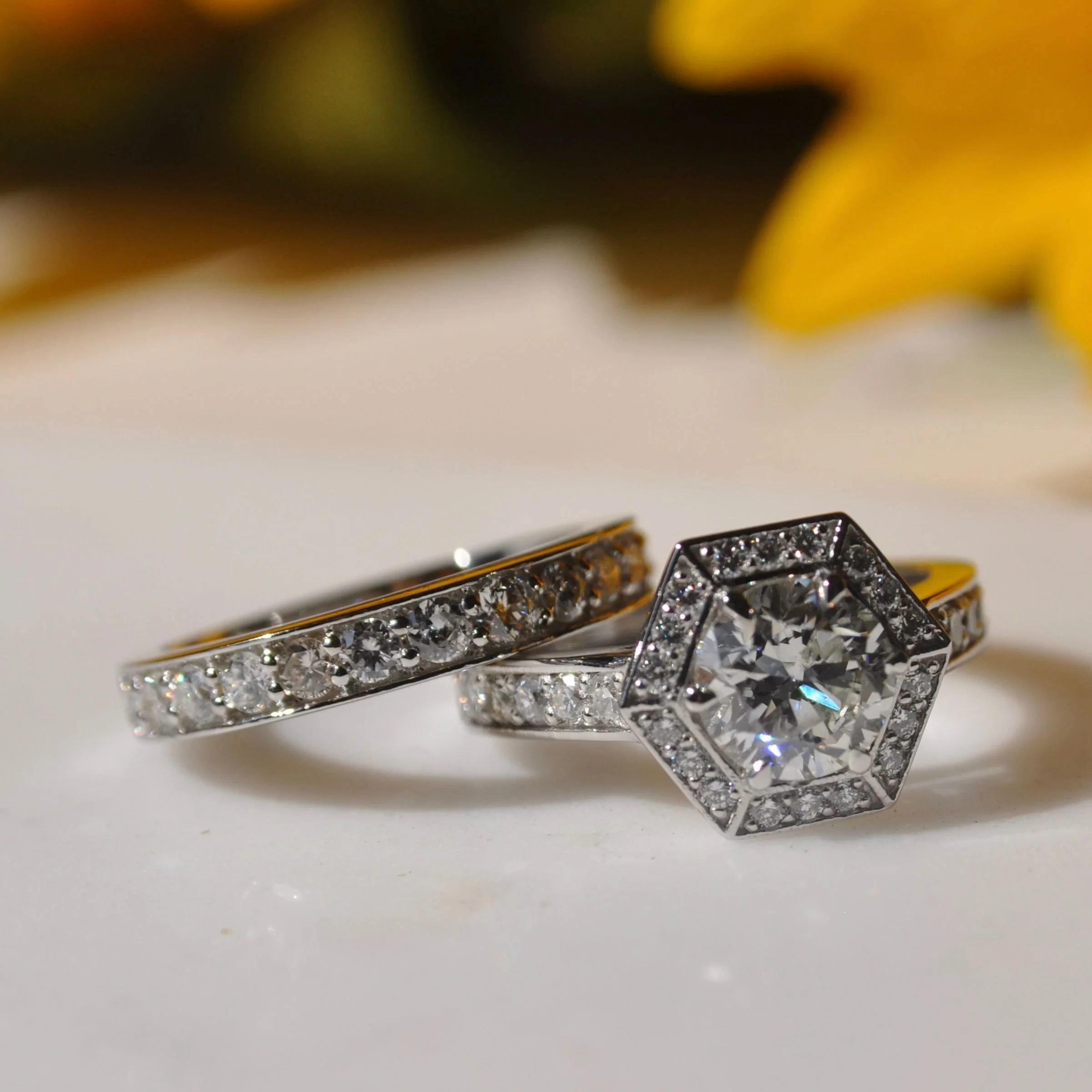 A diamond platinum wedding set featuring a hexagonal halo engagement ring with a round center diamond and a matching pave diamond platinum wedding band.