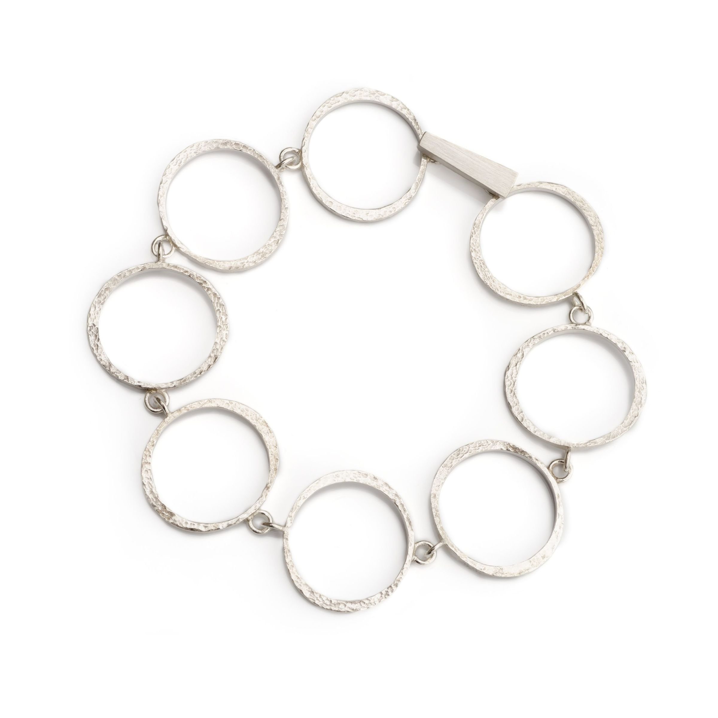 Handcrafted sterling silver mini circle link bracelet arranged in a circle on white background