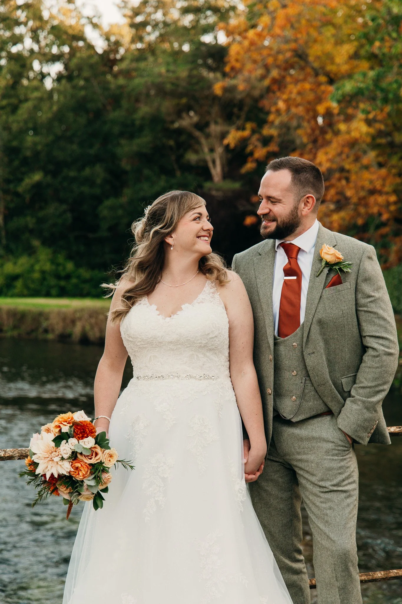 A happy couple on their wedding day, on a bridge at Kimbridge Barn, in Hampshire.