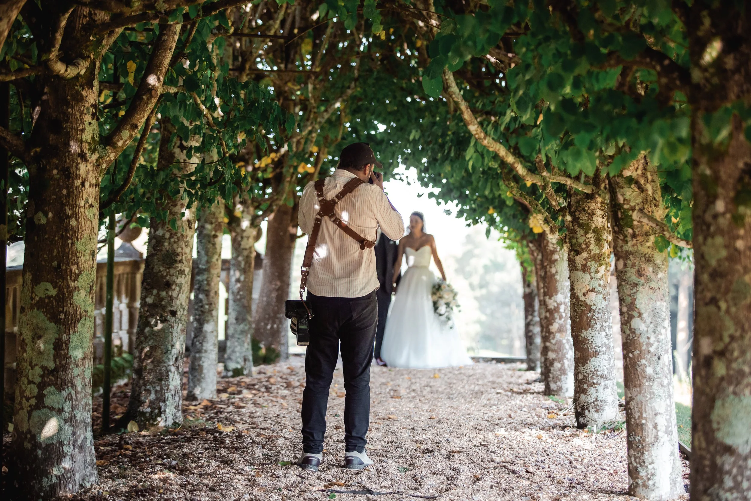 A photographer taking pictures of a bride in a wedding dress in a wooded outdoor setting. Matthew Johnston Photography, Hampshire, UK.