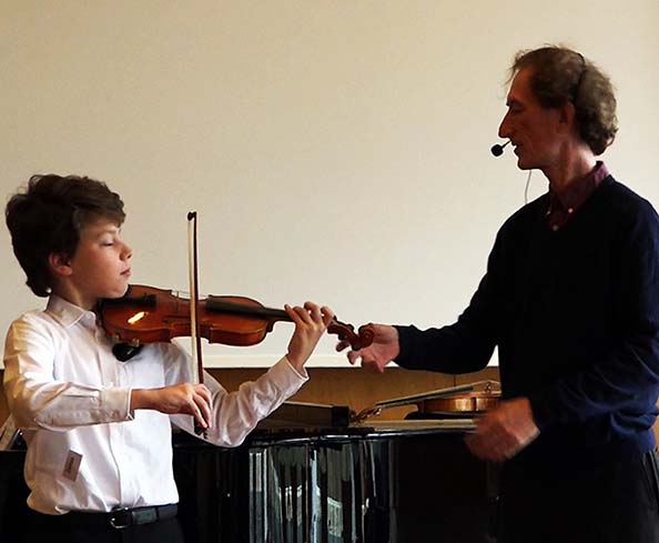 Here's Simon Fischer stabilizing a student's violin, closing the chain, perhaps to focus on a left hand concept, alignment, or bow concepts.