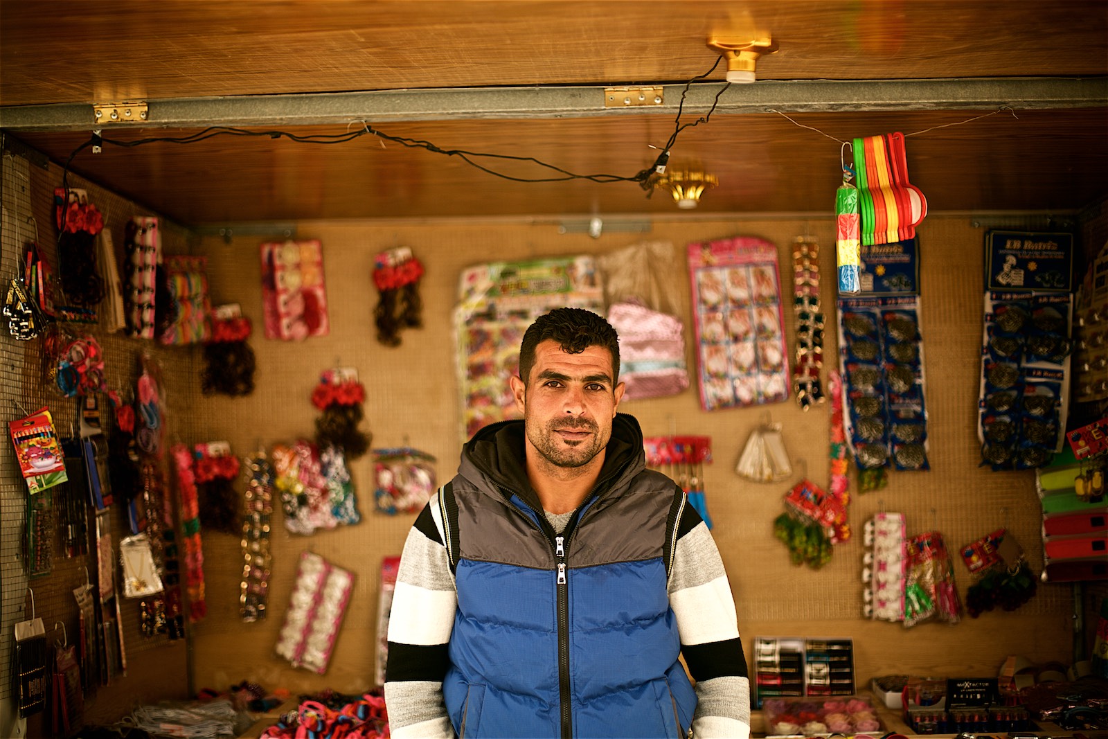  Rahman (name changed) in front of a shop where he works. He says it helps him sustain his family, however, he sees no future for himself in the camp and has decided to go back the first opportunity he has.&nbsp;(photo: Denis Bosnic) 