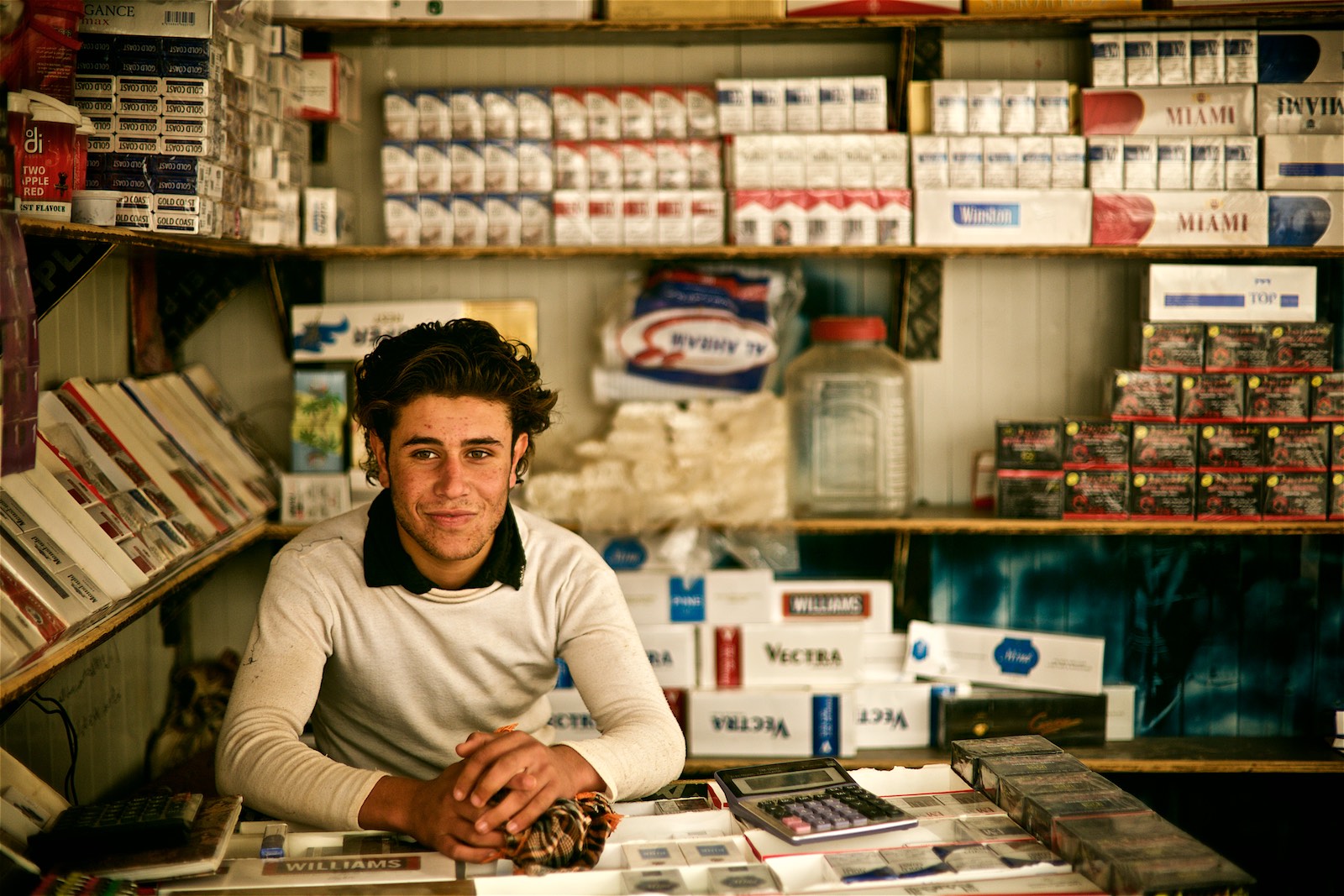  Majd, a 17-year old teenager from Dara'a, is a local cigarette vendor. He says he fled the conflict with his family and is happy to be safe, but is desperate for achieving more than just sitting in a cigarette booth.&nbsp;(photo: Denis Bosnic) 