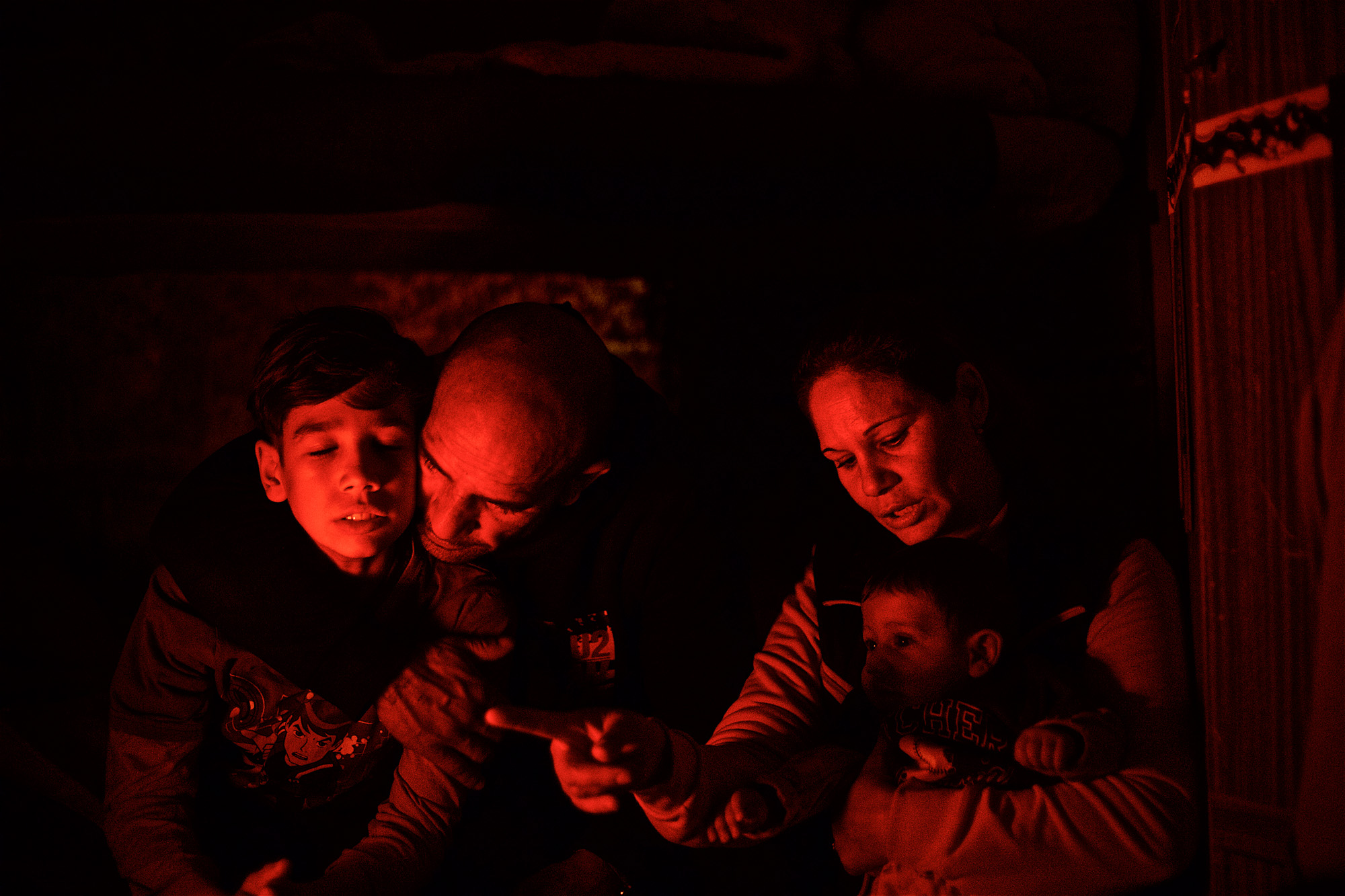 Ramadan, Elena, and their two sons enjoying the heat from an electric heater in their trailer home at the outskirts of Rome. Ramadan is stateless and due to lack of recognition by the authorities, he has been fighting an uphill battle to provide stability for his family. (December 2015) | Photo: Denis Bosnic