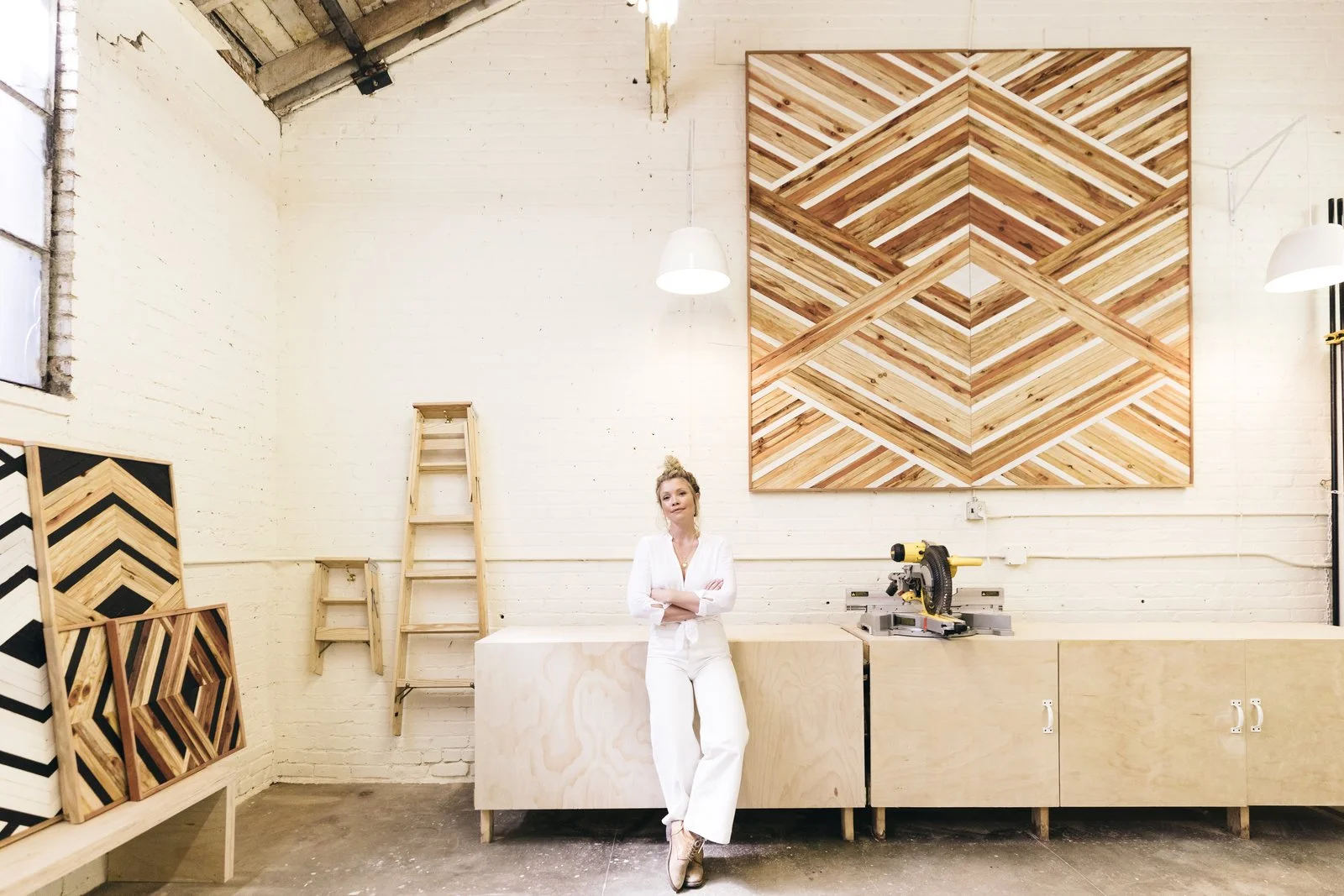 Zee proudly stands in front of her new large-scale piece in her Oakland workspace.