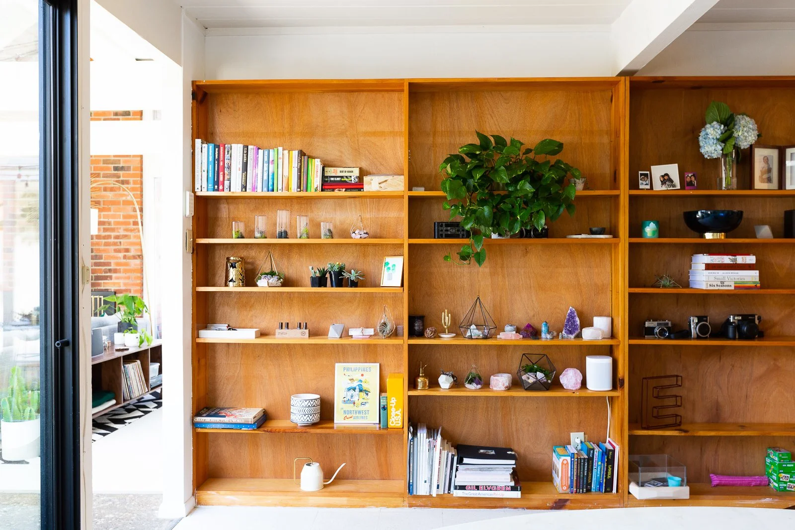 The bookshelf across from the breakfast nook holds favorite books, crystals, plants, and vintage cameras. (Gillian Walsworth)