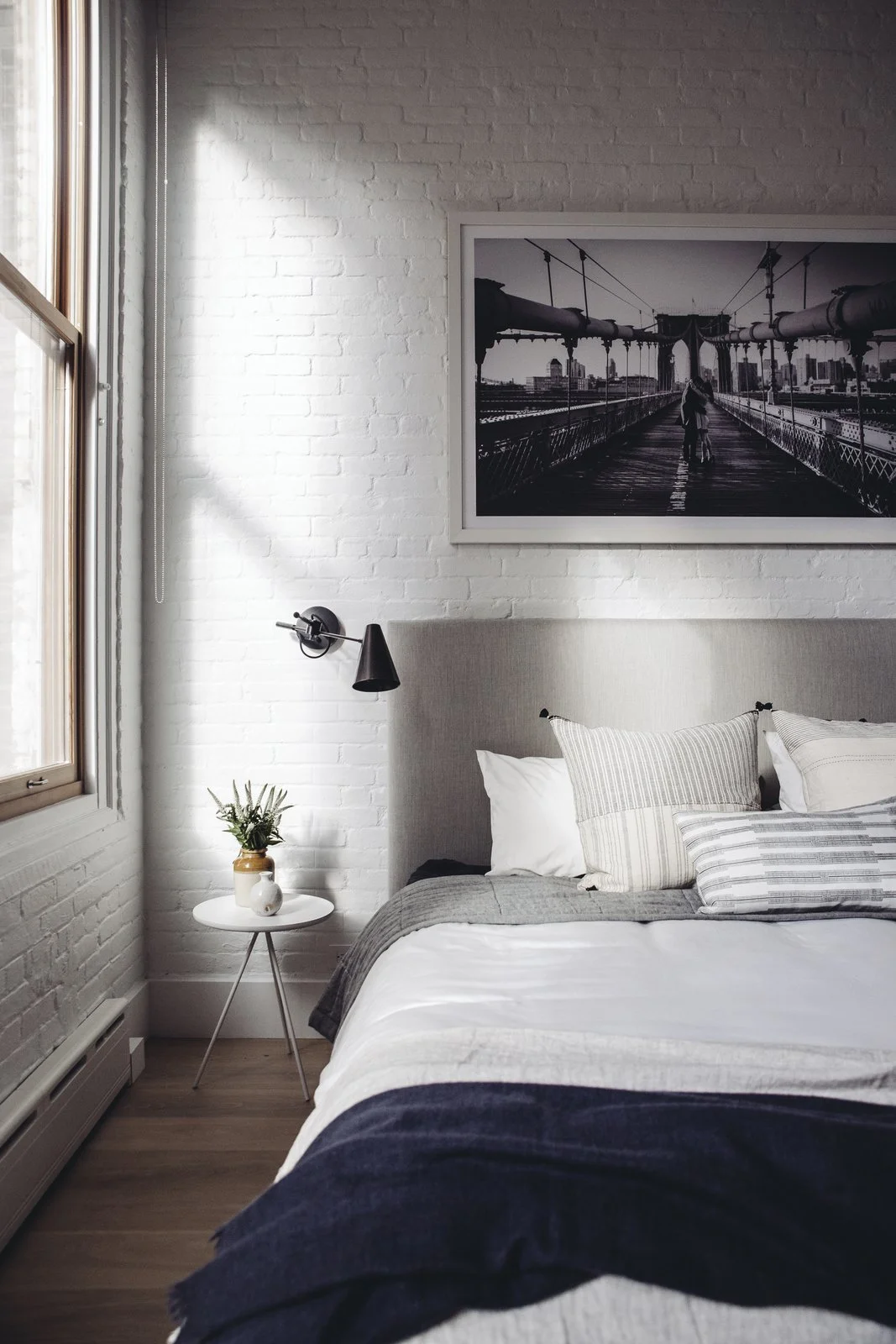 Exposed brick and natural light add a touch of quintessential New York loft style to the updated home. Restoration Hardware sconces, pillows from Injiri and Susan Connor, and a throw from ABC home tie the room together in the perfect combination of structured and cozy. (Chloe Leroux)