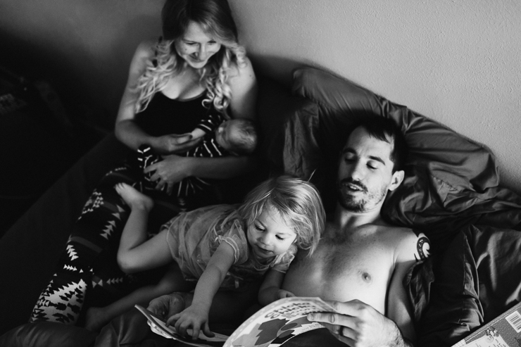 Family of four snuggling in bed at bedtime