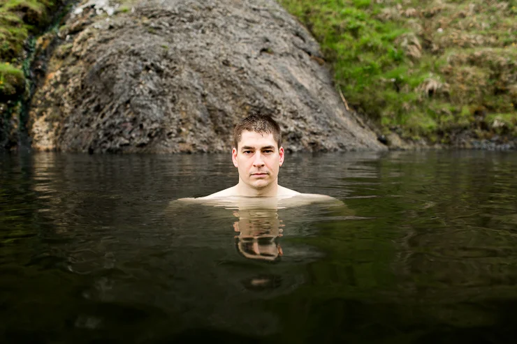 man swimming in Seljavallalaug 1923 geothermal pool, Iceland