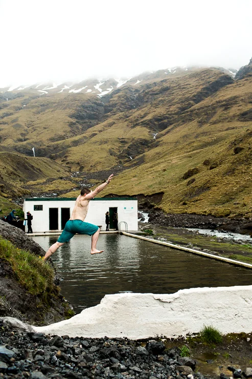 man jumping into Seljavallalaug 1923 geothermal pool, Iceland