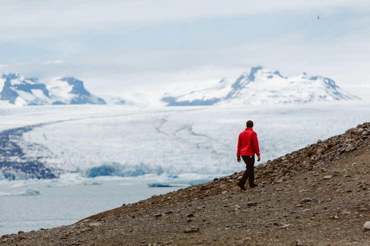 Man in red coat walking near Jokulsarlon Glacier Lagoon, Iceland