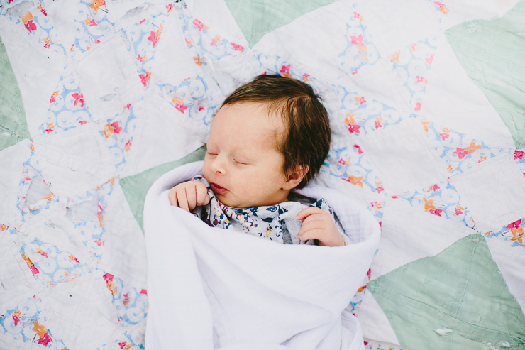 Newborn baby laying on a quilt