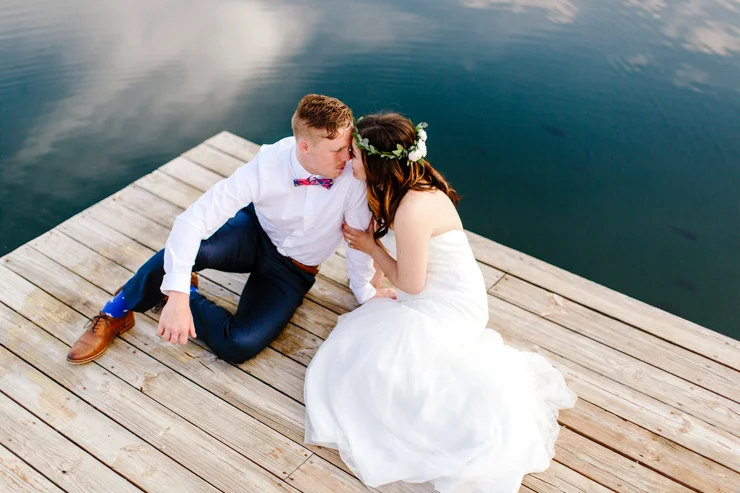 Bride and Groom Portraits sitting on a dock by the lake at a childhood home