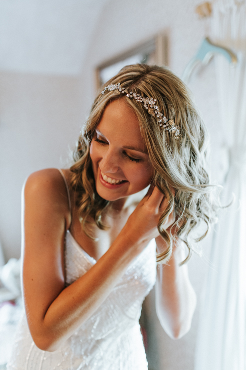 Bride wearing BHLDN wedding gown and putting on her earrings