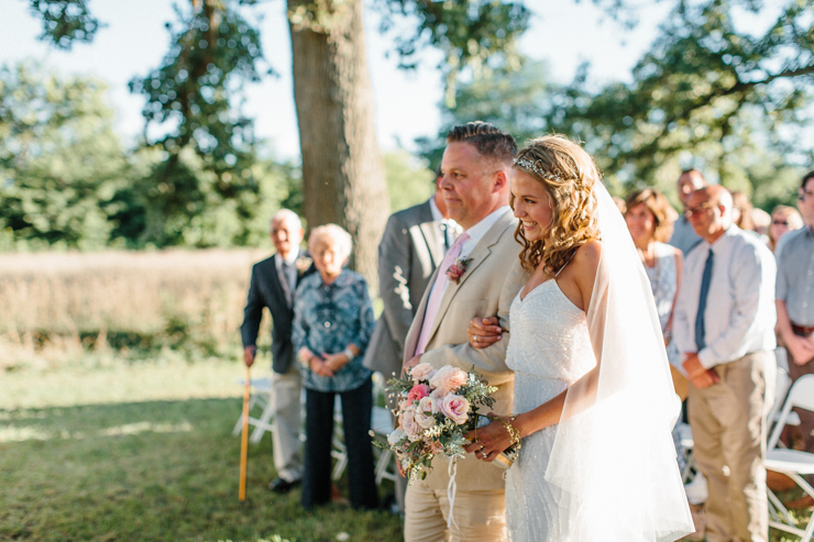 Bride walking down the aisle with her father outdoors and grandparents' farm