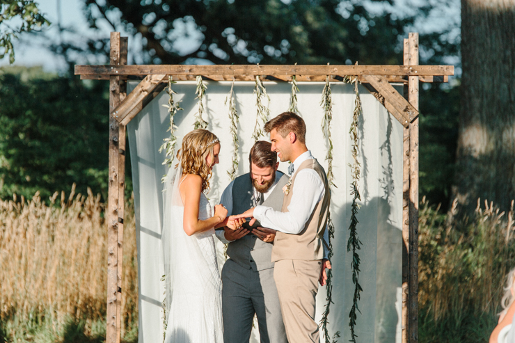 Bride and Groom giving one another rings during outdoor wedding ceremony on grandparents' farm