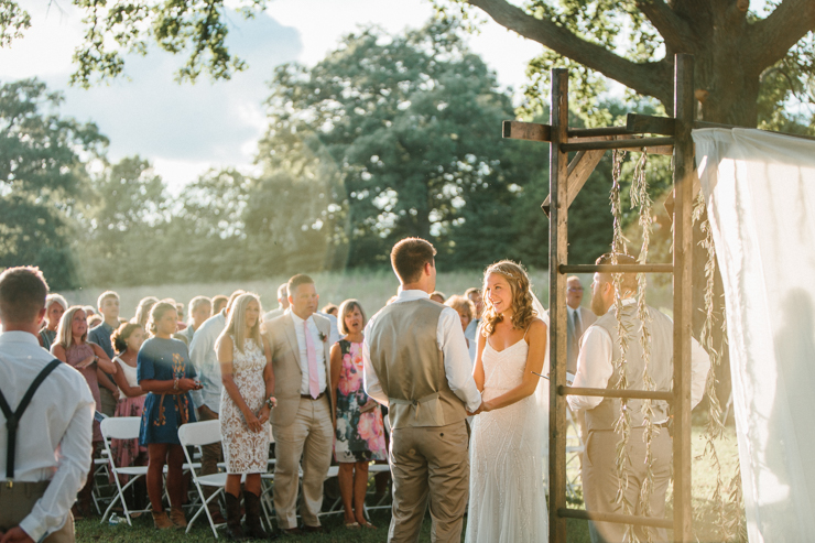 Bride and groom saying vows at outdoor wedding ceremony at sunset on grandparents' farm