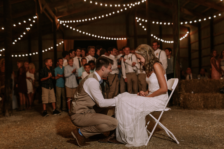 Garter toss at midwest barn reception lit with edison bulbs