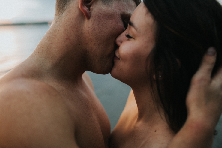 Intimate photography of a married couple in the water together partially nude 