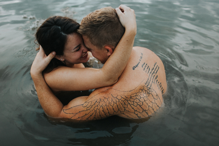 Intimate photography of a married couple in the water together partially nude 