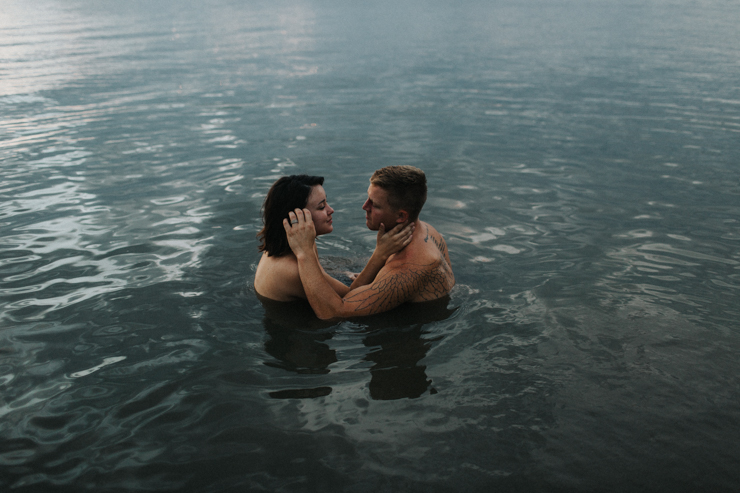 Intimate photography of a married couple with amazing tattoos in the water together partially nude