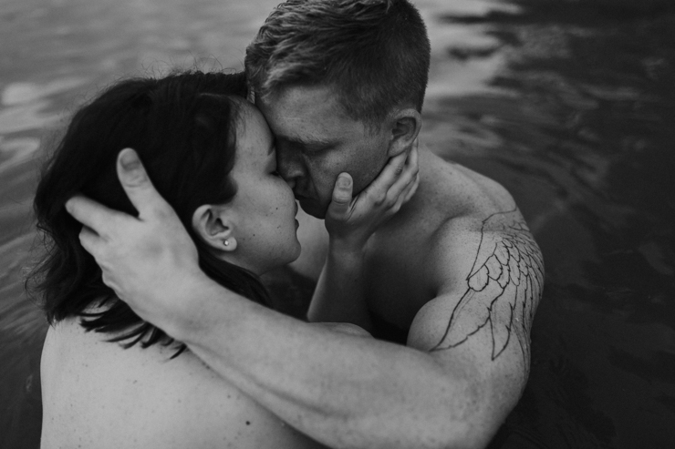 Intimate photography of a married couple with amazing tattoos in the water together partially nude