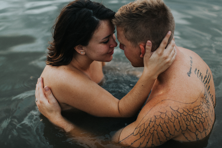 Intimate photography of a married couple with amazing tattoos in the water together partially nude