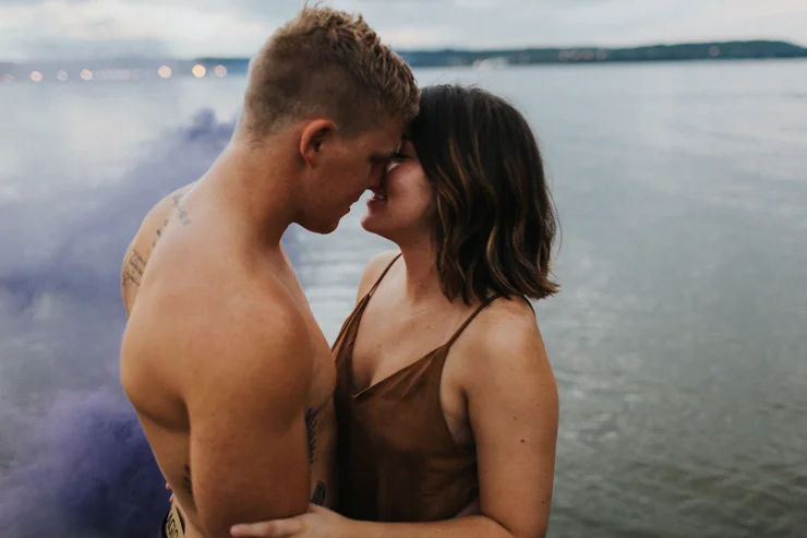 Intimate couple photography nude in the water with a purple photography smoke bomb