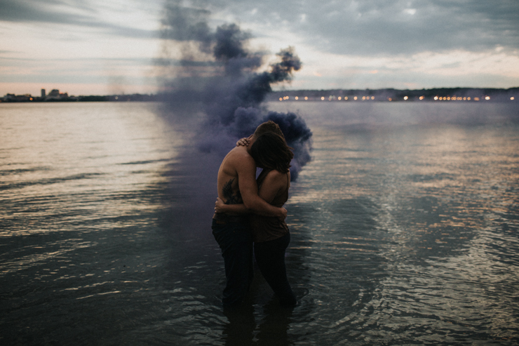 Intimate couple photography nude in the water with a purple photography smoke bomb 