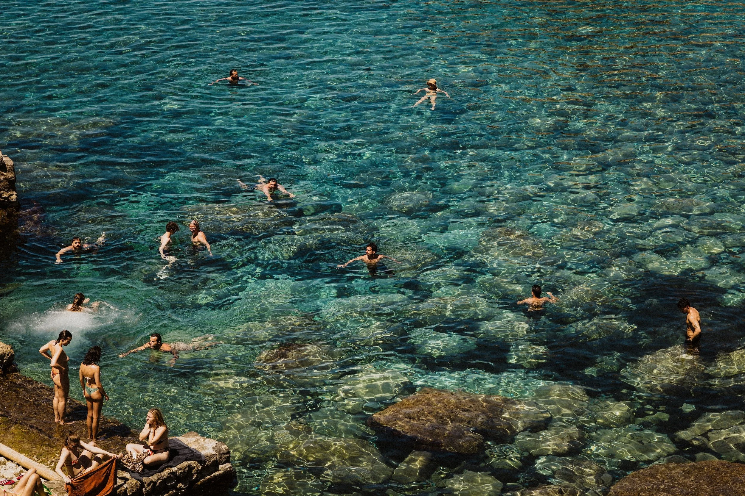 Swimmers in turquoise Mediterranean water at Deià Beach, Mallorca