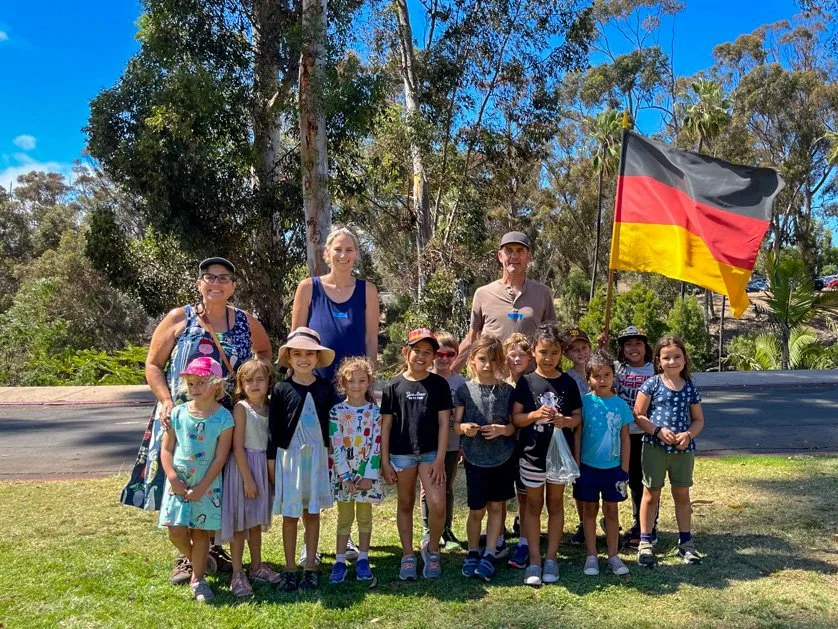 Group of Kinderwerkstatt students posing with their teachers and holding a German flag.