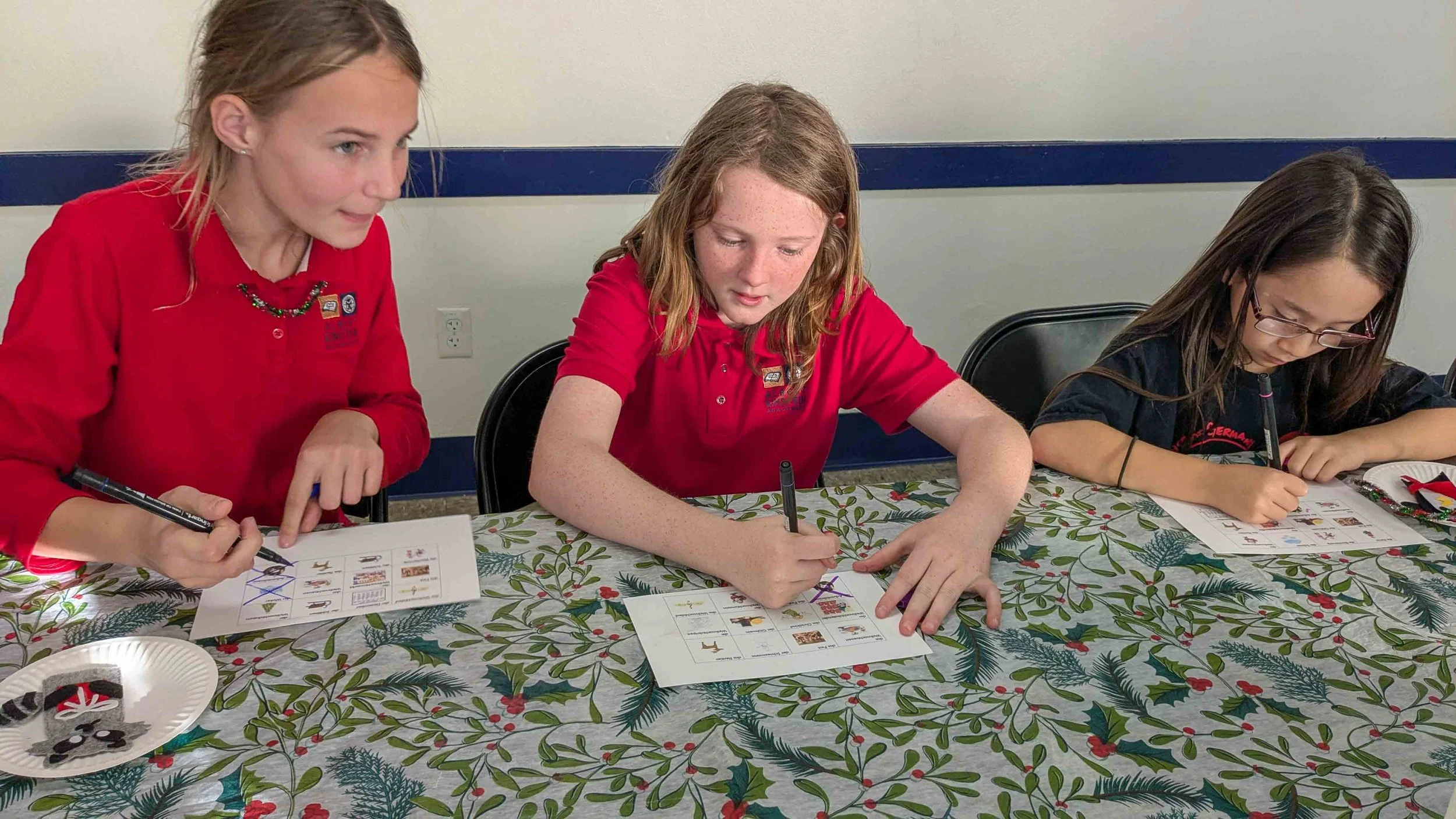 Three Kinderwerkstatt students sitting at a table completing a worksheet.