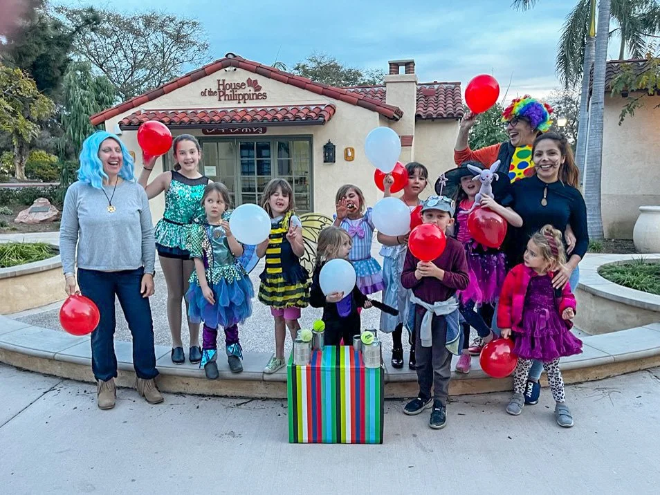Group of Kinderwerkstatt students and their teachers dressed in colorful costumes, celebrating outside near the International Cottages.