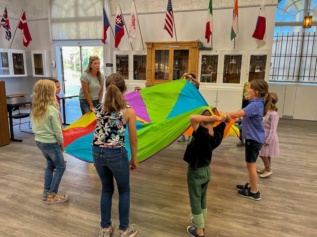Kinderwerkstatt students playing with a colorful parachute at the HPR Hall of Nations.