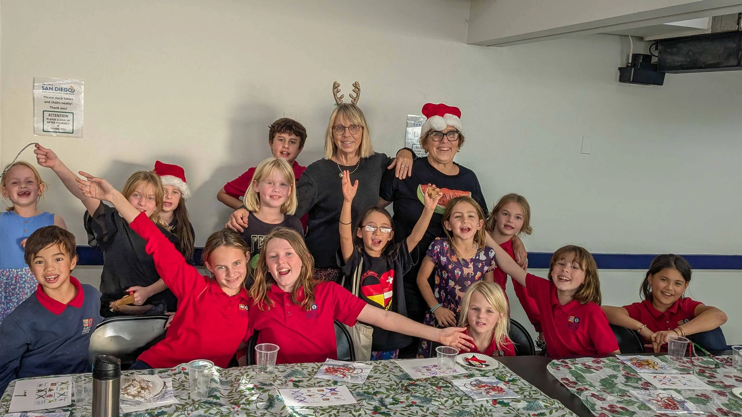 Group of Kinderwerkstatt students posing with their teachers, with a few of them wearing festive hats.