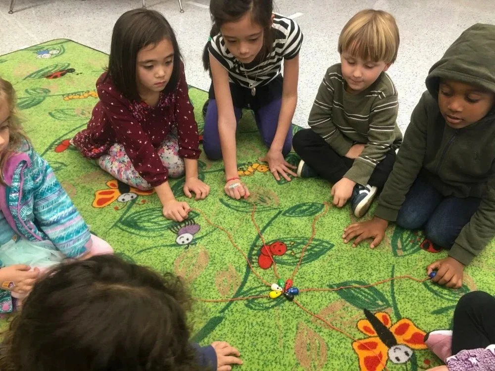 Kinderwerkstatt students sitting on a rug, participating in an activity.