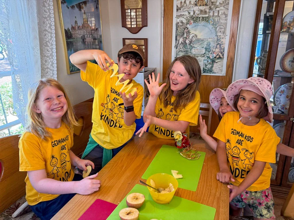 Summer camp participants at the House of Germany cottage, holding a sliced apple.