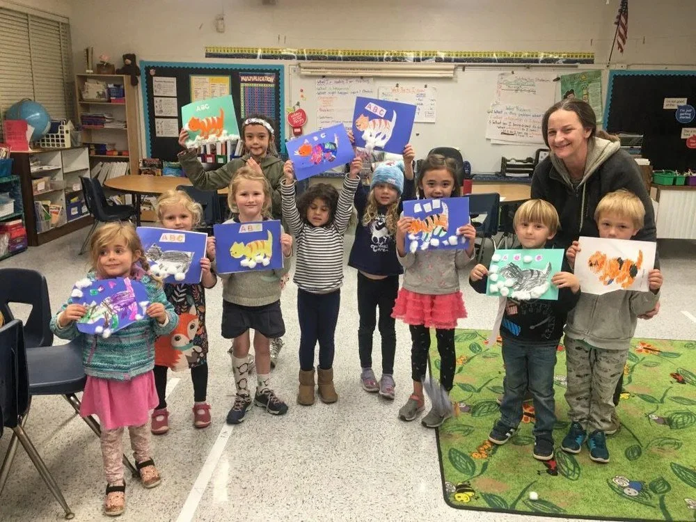 Preschool classroom with Kinderwerkstatt students holding up their colorful artwork of animals.