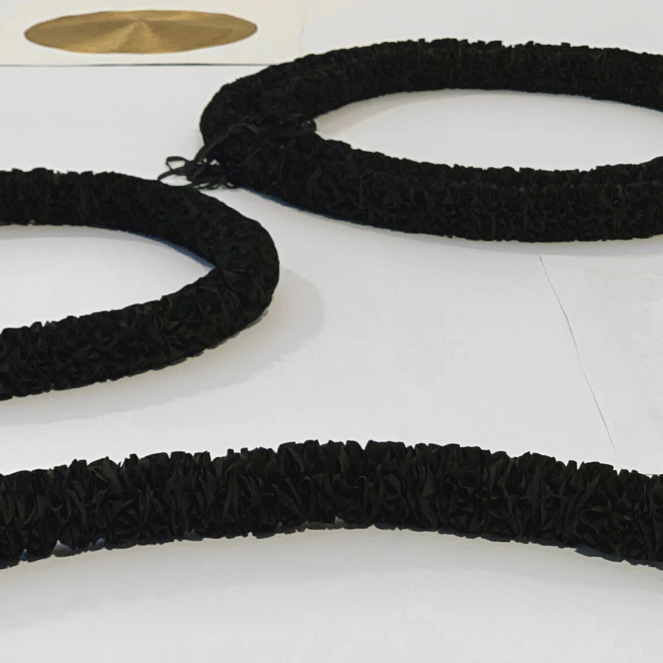 Anne Wilson, Absorb/Reflect , 2020Mourning Garlands nos. 1, 2, 3... (ribbon, thread). Golden Roundels nos. 1, 2 (damask table napkin, ink, gold thread embroidery). Installation on floor platform, 132 x 64 inches. Photo: Anne Wilson Studio