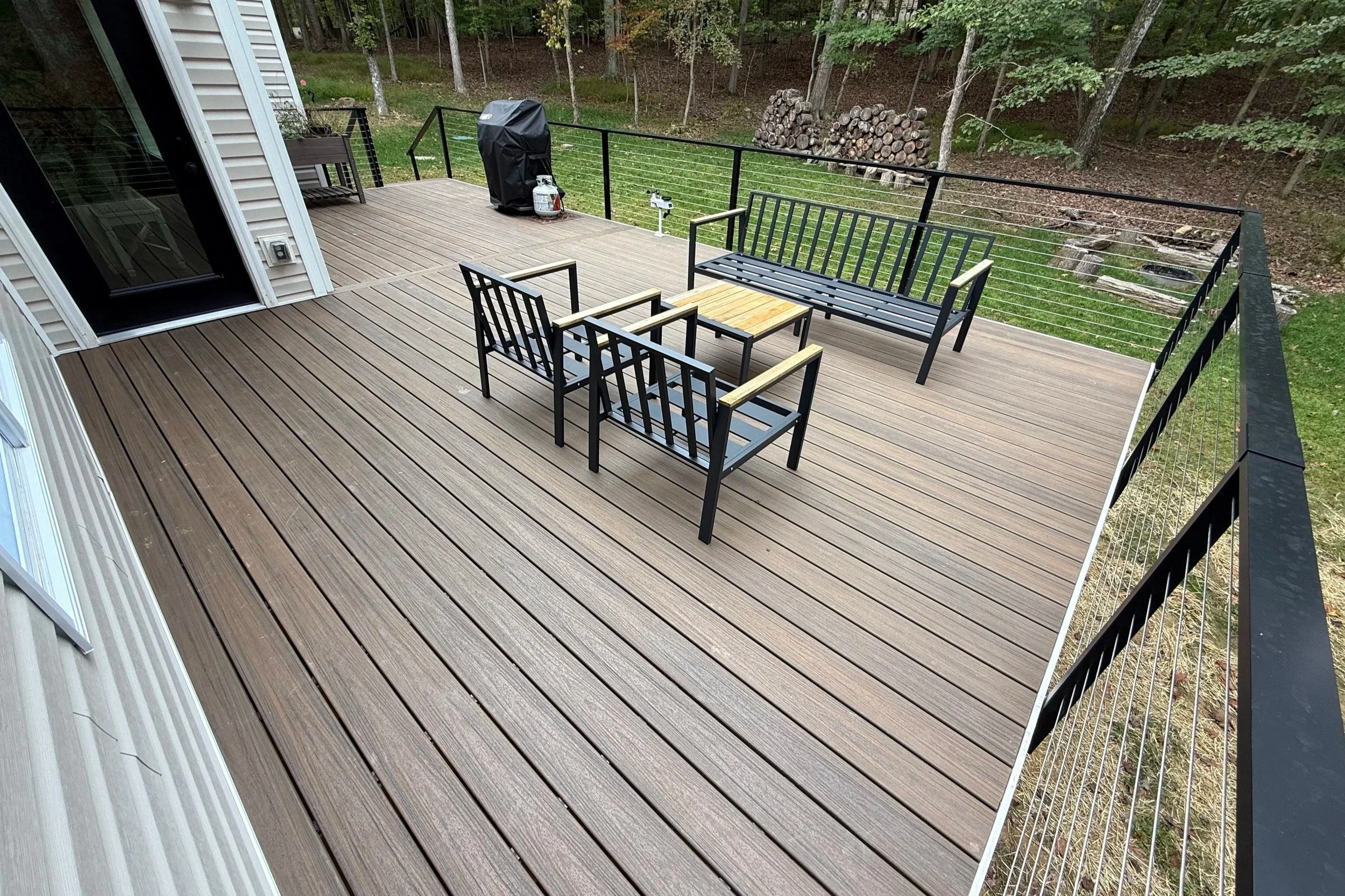 Contemporary brown composite deck featuring black metal railings and a matching outdoor furniture set.