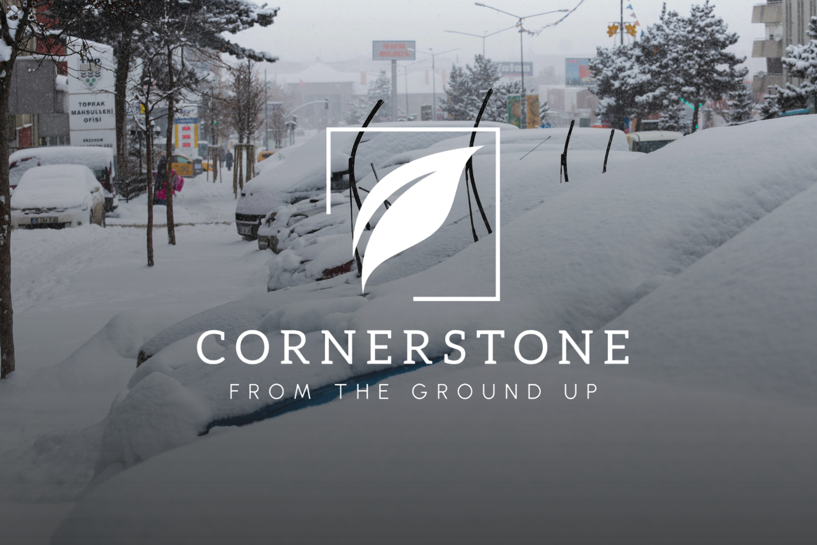 Cornerstone Lawn Services logo and "From the Ground Up" slogan overlaid on a background of cars covered in deep snow on a winter day.