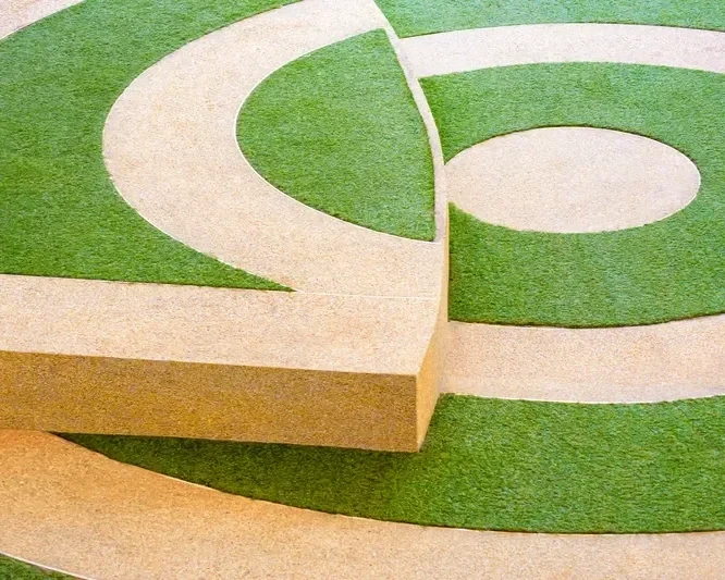 Modern landscape design featuring green artificial turf inlaid with geometric circular aggregate concrete paving.