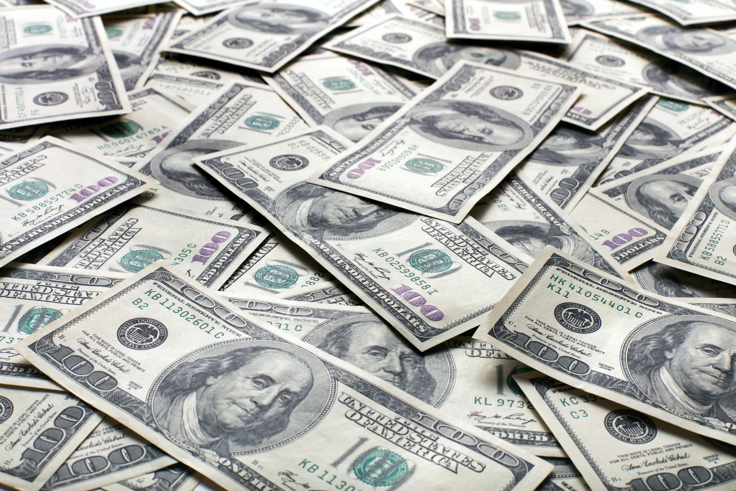 Large pile of scattered one hundred dollar bills, representing wealth, cash flow, or financial savings.