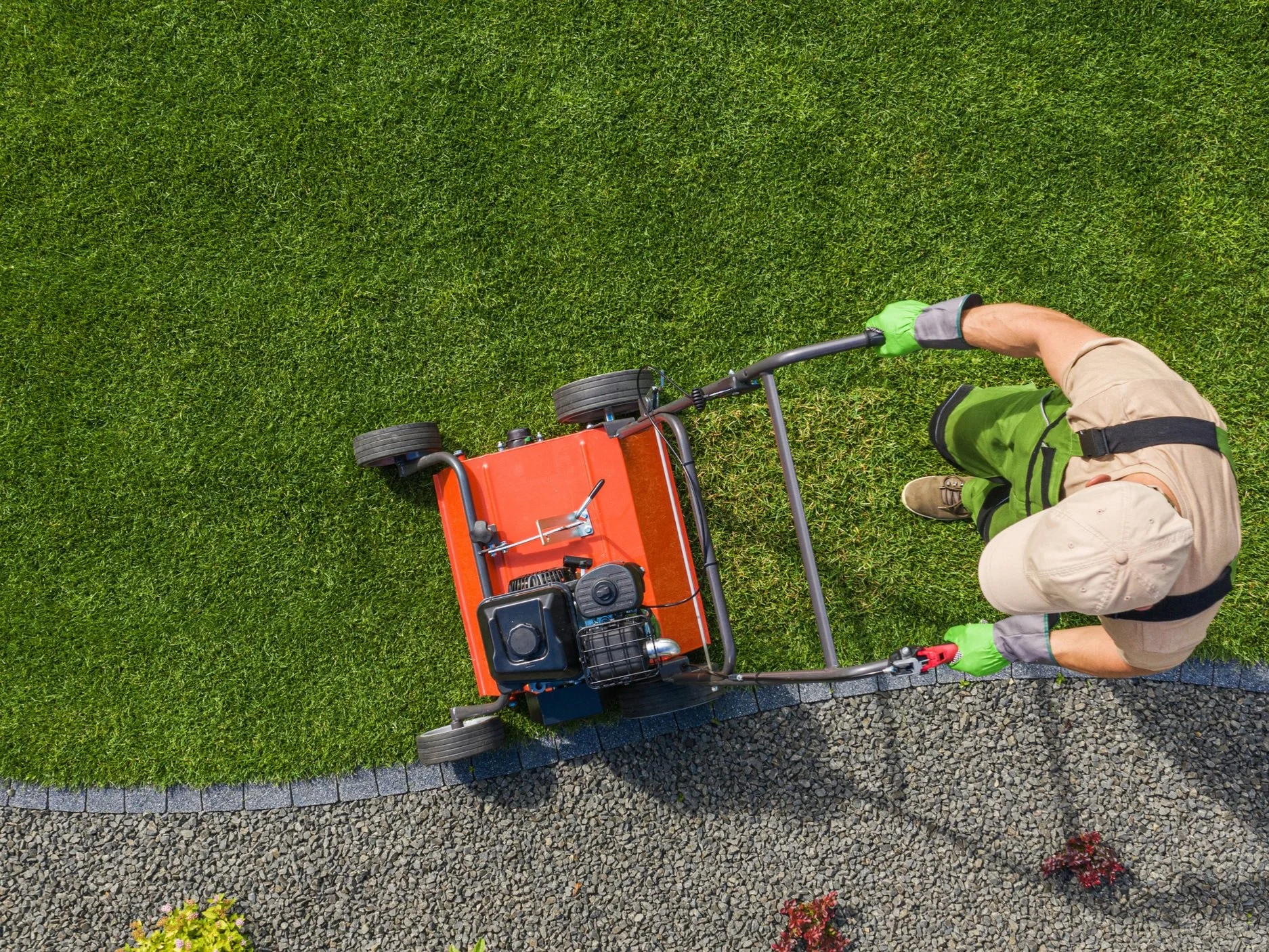 Overhead view of a landscaping professional using a core aerator machine on a lush green lawn.