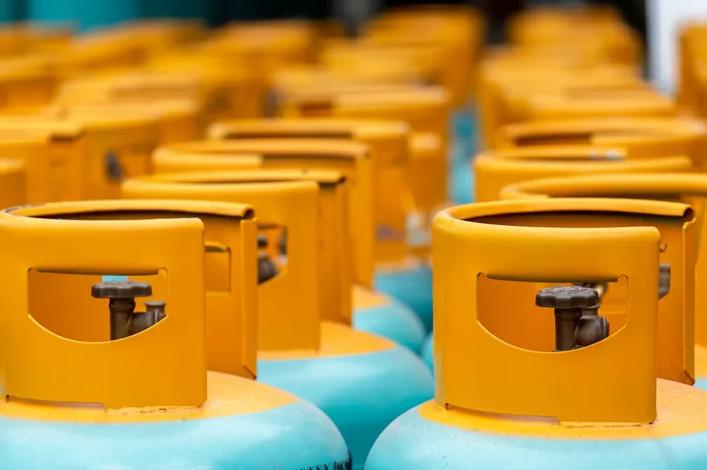 Rows of vibrant yellow and blue propane gas cylinders lined up closely together in a storage or supply area.