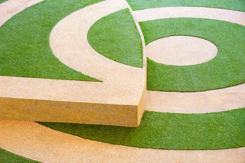 Modern landscape installation featuring green artificial turf inlaid with circular concrete walkways and stepping platforms.