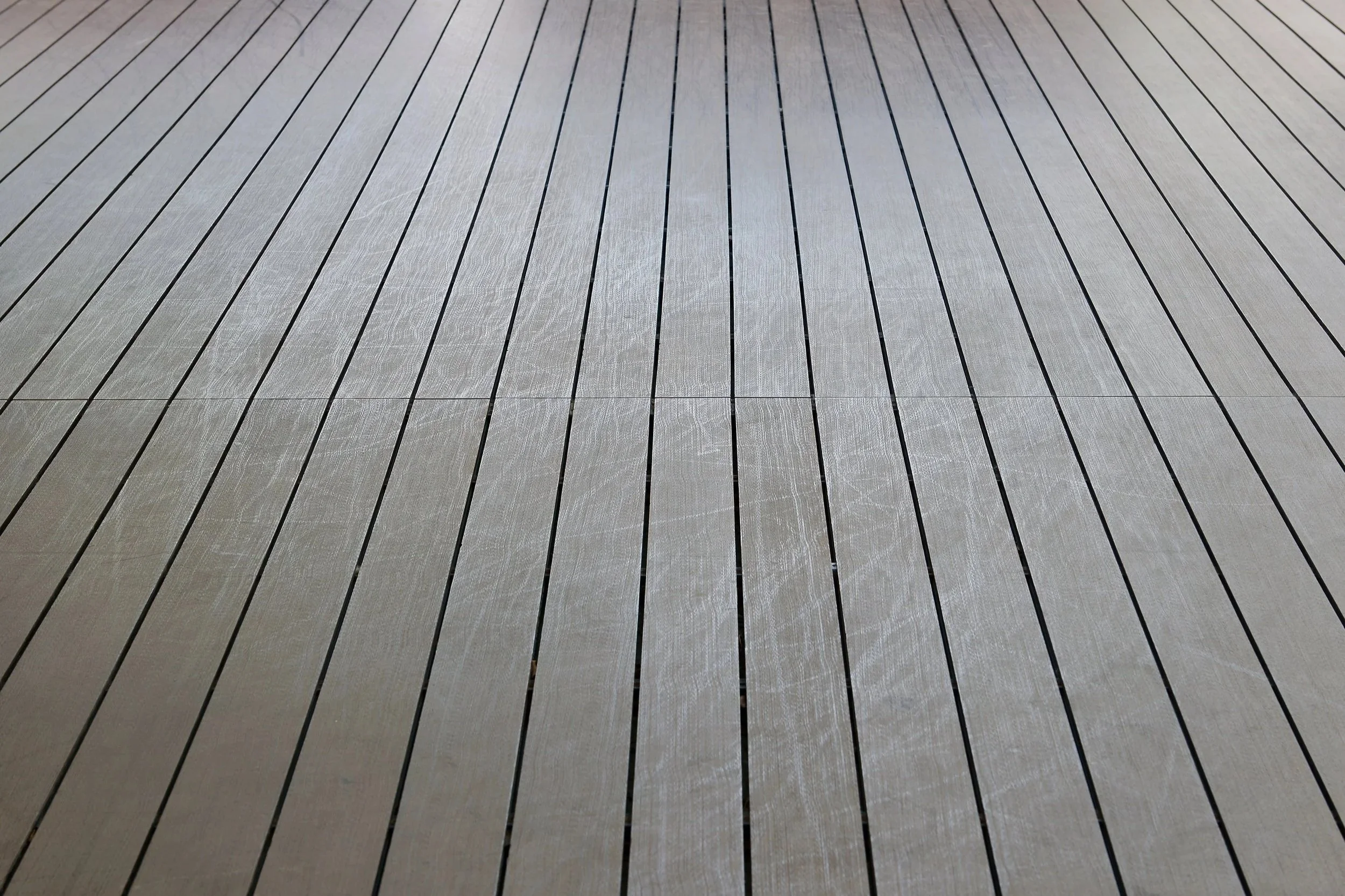Detailed view of light gray composite deck boards with a non-slip texture and uniform parallel lines.
