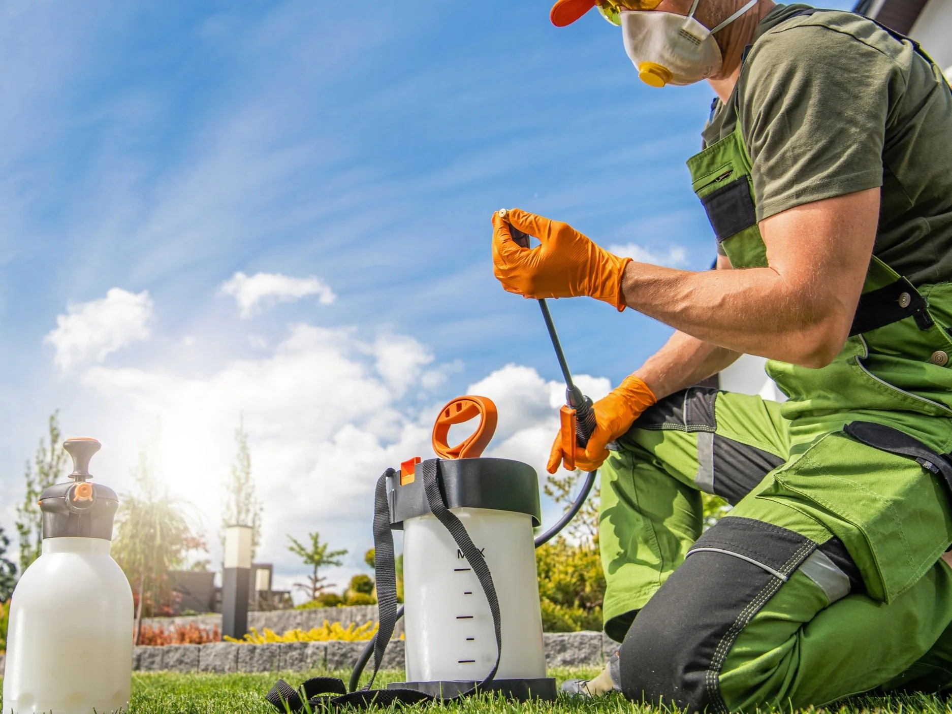 Lawn care technician in safety gear preparing a professional sprayer for weed control and fertilization.