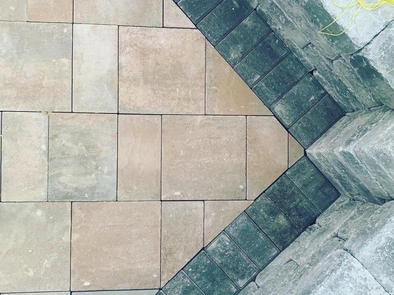 Close-up of tan interlocking patio pavers with a contrasting dark gray stone border.
