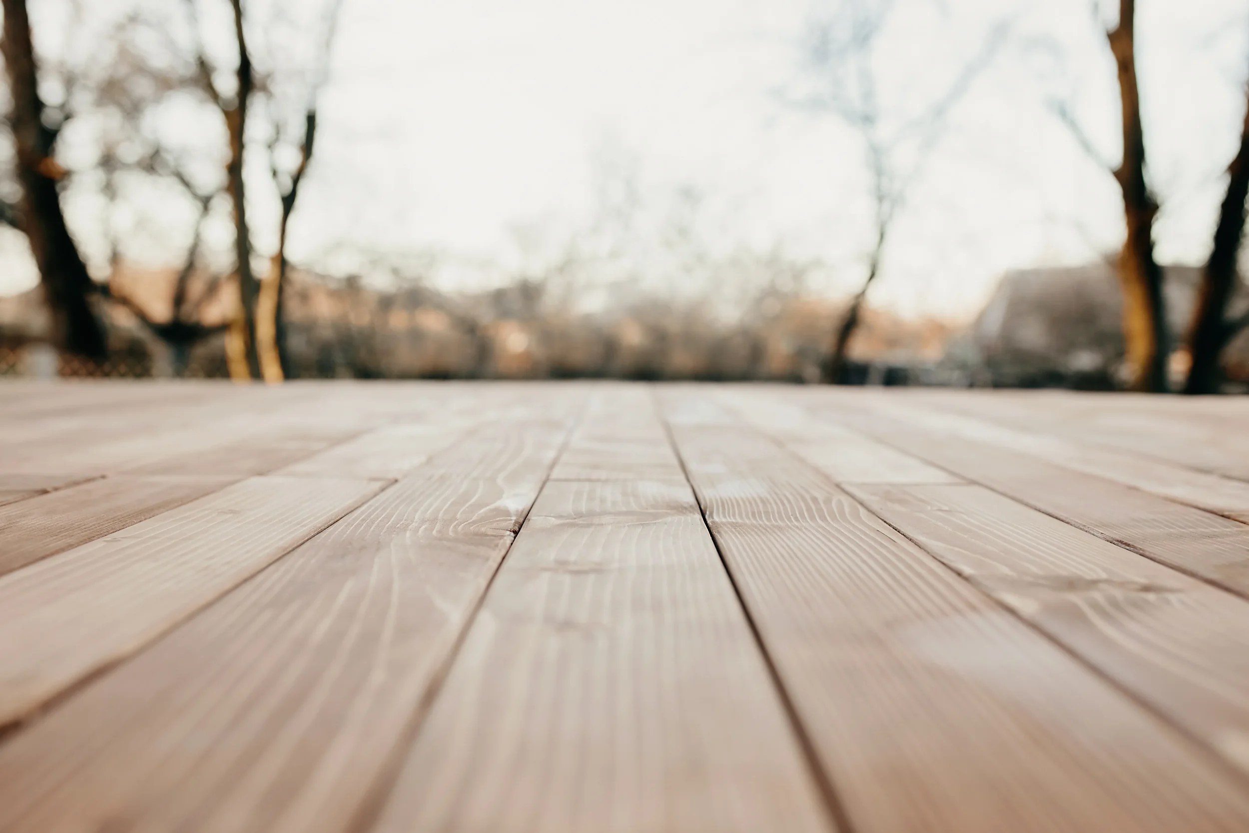 Outdoor deck banner with text "Elevate Your View with Custom Decks" over a diagonal wood plank background.